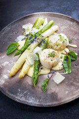 Traditional gourmet gegrillte Jakobsmuscheln mit grünen und weißen Spargel und Sauce Hollandaise angeboten als close-up auf einem rustikalen Modern Design Teller