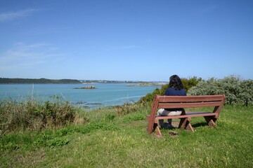 Femme assise sur un banc face à la mer