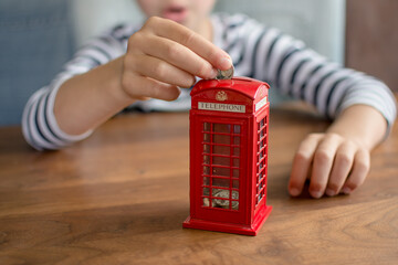 hand putting coin to the coin box look like traditional british call box, saving money concept