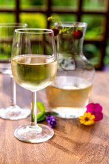 Summer tasting of cold white wine on sunny garden terrace with wooden pergola