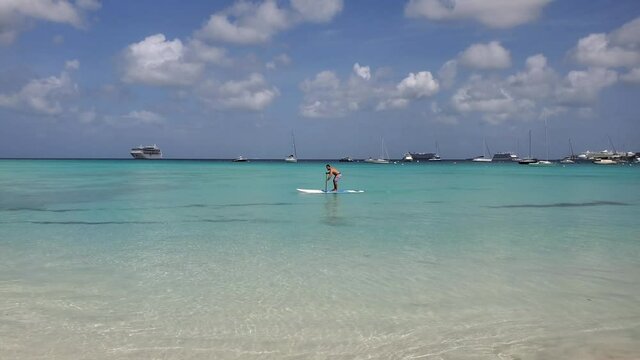 Black African American man surf SUP paddleboard lesson in blue sea of Caribbean diversity