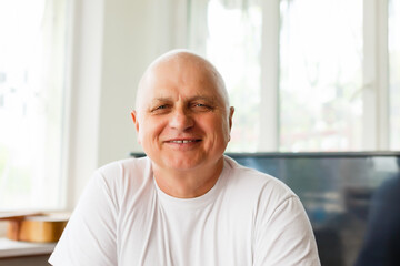 Elderly man with headphones and computer laughing happily, telework, e-business or commerce,...
