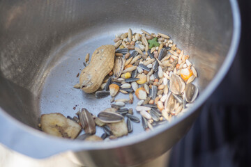 A pile of birds food: Mixture of grains and seeds for parrots, in a metal bowl