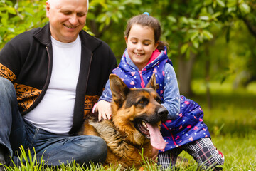 Grandfather with granddaughter and a dog in the garden