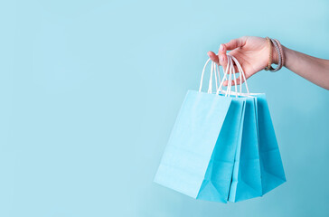 woman hand carrying a bunch of blue shopping bags over blue background
