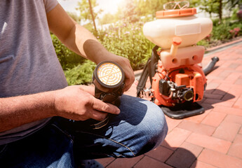 Gardener in protective mask and glasses spraying toxic pesticides trees
