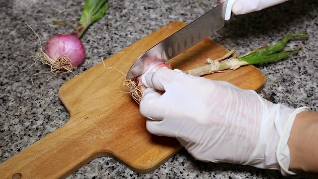 Chef's hands chopping onion and garlic seen from above