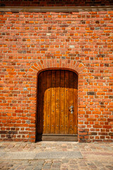 Old wooden gates and walls of red brick.