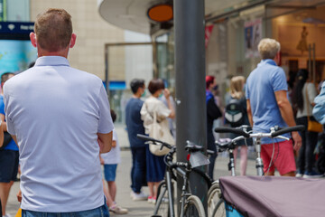Fototapeta premium Selected focus view, man with face mask queue and wait for enter a shop on sidewalk outside store during social distancing and quarantine regulations for COVID-19 virus in Düsseldorf, Germany.