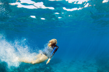 Happy family - active teenage girl jump and dive underwater in tropical coral reef pool. Travel...