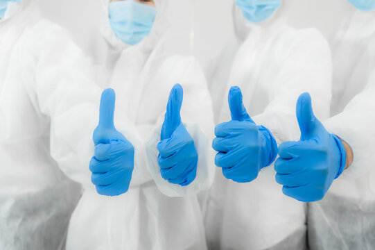 Team of medical scientific researcher standing wear safety suit and personal protective equipment with thumbs up in lab.