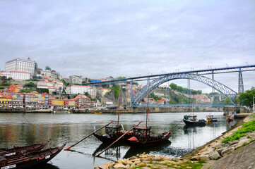 Obraz premium Ships with barrels of wine on the Duoro River in Porto with a view on Eiffel's bridge. 