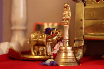 Stock photo of a brass pooja room bell with temple deity in background. It drowns inauspicious...
