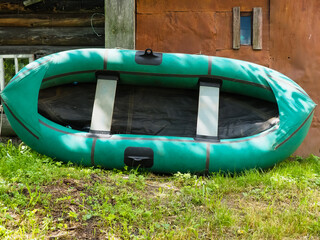 a green rubber boat leaning on a shed.