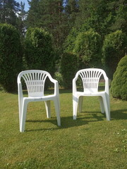 two white plastic chairs stand on the lawn, garden furniture
