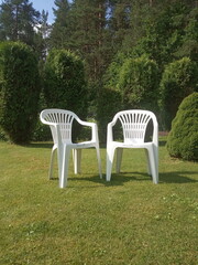 two white plastic chairs stand on the lawn, garden furniture

