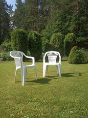 two white plastic chairs stand on the lawn