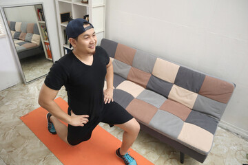 Asian male doing exercise at home to stay healthy on new normal lifestyle, indoor home workout, ...