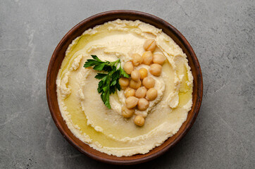 Flat lay view at hummus topped with chickpeas and green coriander leaves on stone table