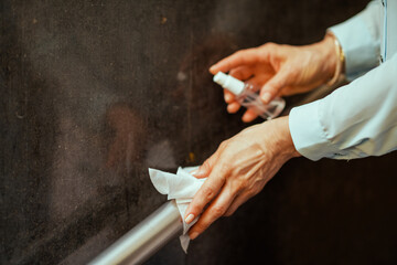 Closeup on woman disinfecting railing with sanitizer
