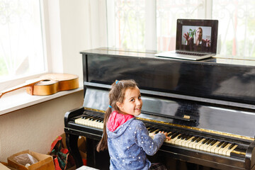 Home lesson on music for the girl on the piano. The idea of activities for the child at home during quarantine. Music concept