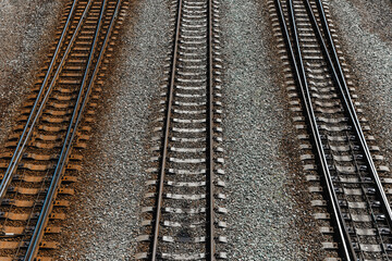 Fototapeta premium Railroad pattern, backdrop with space for text. Top view. Iron rails and concrete sleepers on stony ground. Old rails