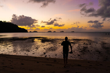 Silhouette of a man on the beach at sunset. Man rejoices meets the sunset