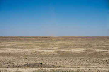 Obraz premium Steppe in the summer. Blue sky and clouds over the steppe. Burnt steppe in the summer. The texture of the earth scorched by the sun. Desert. 