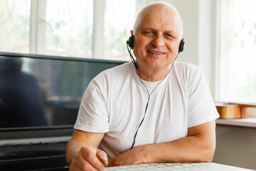 Fototapeta premium Head shot close up happy grandfather looking at camera, talking to grown up children or communicating via video call with friends, sitting on sofa at home. Pleasant old man involved in conversation.