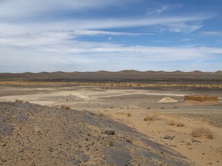 Sandy landscape under blue sky with white clouds, near Merzouga, Morocco