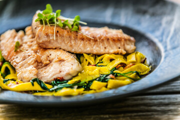Grilled salmon fillet with homemade fettuccine pasta on a plate. The food in the restaurant. Food styling and restaurant meal serving. 