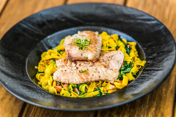 Grilled salmon fillet with homemade fettuccine pasta on a plate. The food in the restaurant. Food styling and restaurant meal serving. 