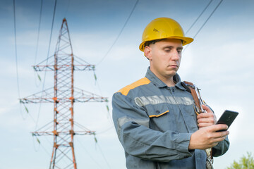 Engineer-worker in protective clothing and a hard hat. Holds. mobile phone in hand. Industry. Energy.