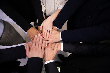Multiracial business people stacking hands together top angle view. Close up pile of african american and caucasian hands of successful team of workers. Teamwork and unity concept