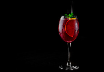 Cold sangria in a wine glass with reflection on black background