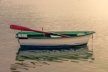 Naklejka premium white wooden fishing boat moored on the shore at sunset