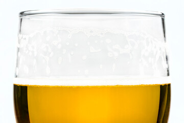 A macro shot of a glass of beer with visible foam and drunk part of beer, isolated on a white background with a clipping path.