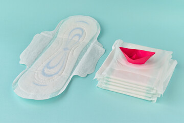 Sanitary napkin with a paper red boat on a turquoise background. The concept of critical days, menstruation. Gynecology. PMS