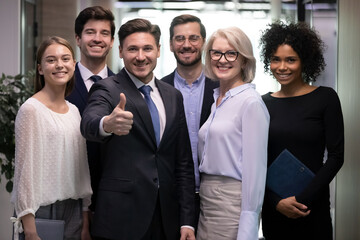 Portrait of successful adult business man with diverse team of happy workers. Senior male leader...