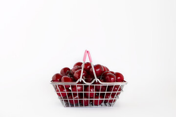 Ripe sweet cherries in small shopping basket isolated on white background with copy space.