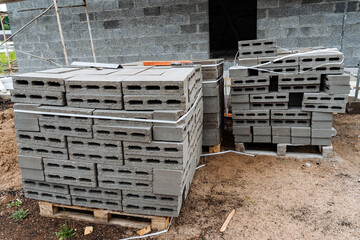 cinder blocks of gray concrete are neatly stacked in a pile, slender rows of bricks, material for building a house