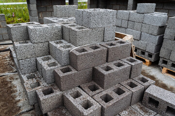 cinder blocks of gray concrete are neatly stacked in a pile, slender rows of bricks, material for building a house