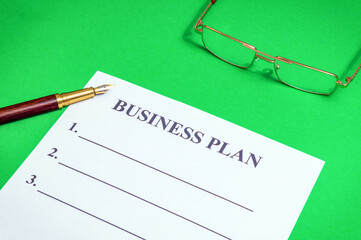 Blank of business plan and stylish pen on a green office desk