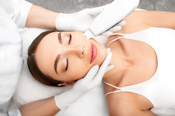 Obraz na płótnie Canvas Woman getting ultrasonic peel skin, a cleansing procedure using a special device. Procedure ultrasonic peeling and cleaning face close-up