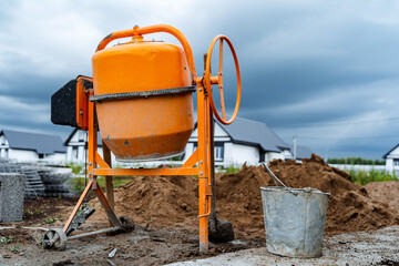 an orange concrete mixer where cement is prepared for construction works stands on the street