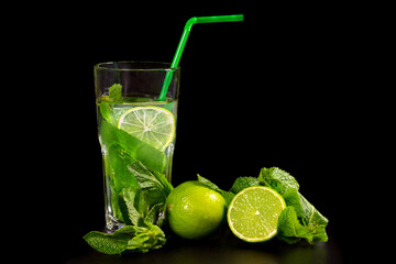 Mojito cocktail drink with fresh mint and lime on a dark background.