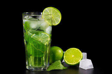 Refreshing summer alcoholic cocktail mojito with ice, fresh mint and lime on dark background.