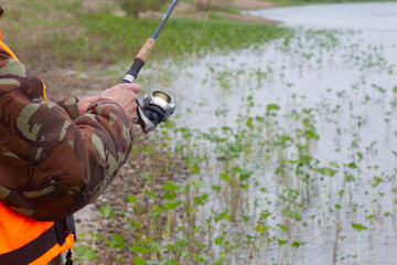 A fisherman with a spinning rod catches fish on the river.