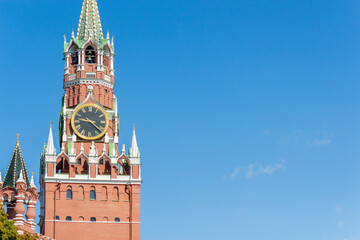 Close up view of clocks on Spasskaya Tower of Moscow Kremlin on a summer morning. Blue sky with few clouds in the background. Copy space for your text.