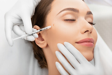 Beautiful woman during facial Mesotherapy. Beautician doing Anti-aging injection for tighten skin.